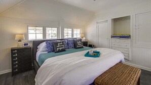 Een slaapkamer met een bed, nachtkastjes, een dressoir en een inloopkast.