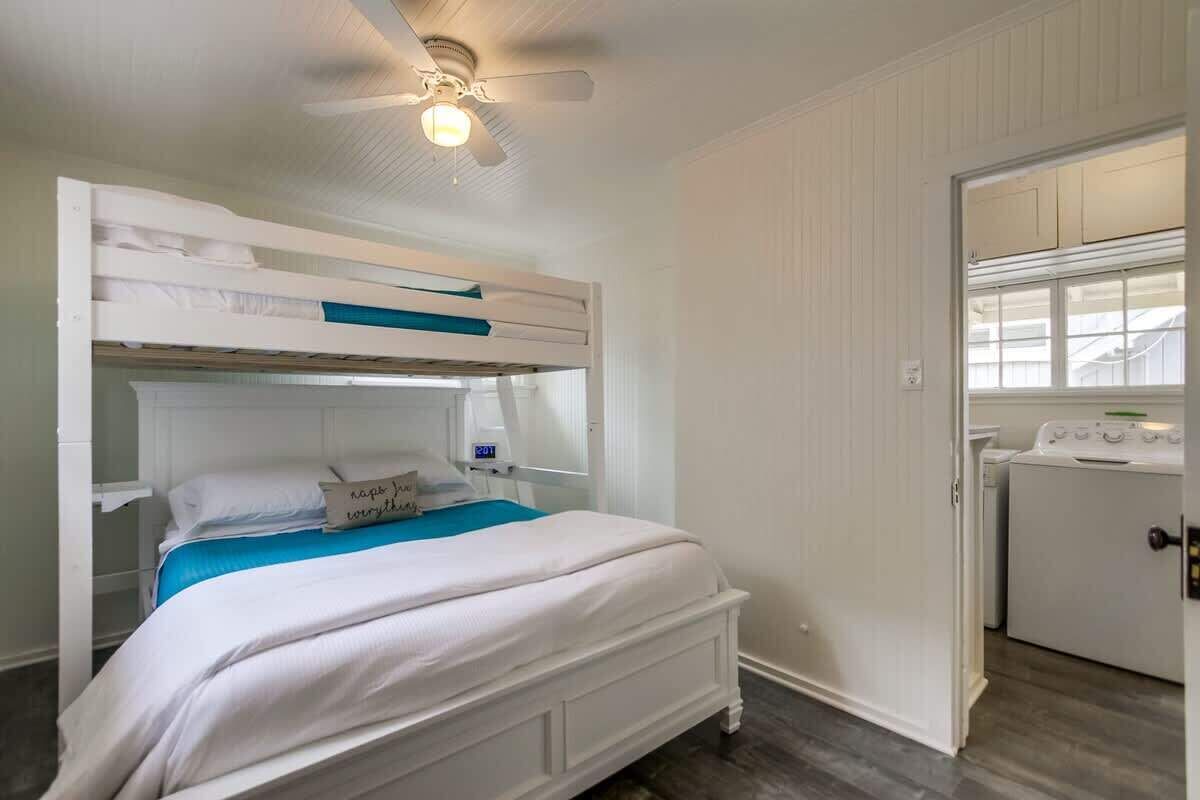 A bunk bed with a ceiling fan, a washing machine, and a window.