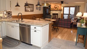 A kitchen with a central island, built-in dishwasher, and a dining area with a fireplace.