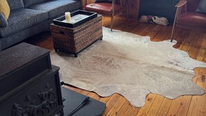 A cozy cabin interior with a wooden floor, a large window, a sofa, a chair, and a fireplace. - Cozy, lakeside cottage for your family vacation (Woodstock)