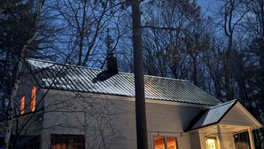A house with a metal roof, a chimney, and a porch with steps leading to a door. - Cozy, lakeside cottage for your family vacation (Woodstock)