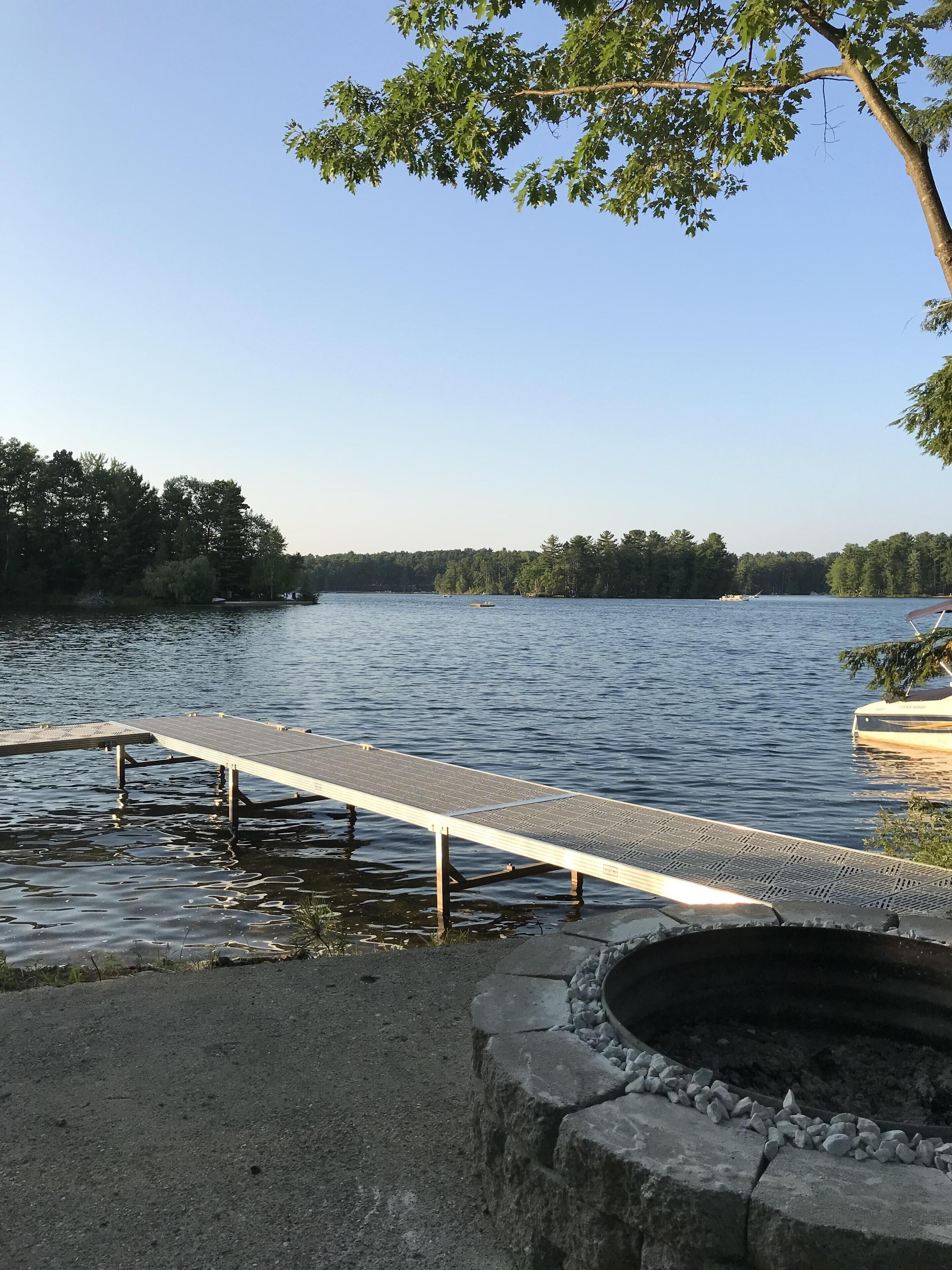 A lakeside dock with a fire pit and a boat.