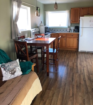 A cozy kitchen with wooden cabinets, a dining table, and a sofa with a cushion.