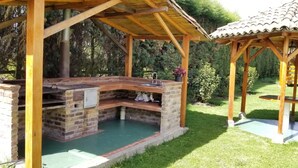 Eine Holzhütte mit Grillplatz aus Ziegelsteinen und einem kleinen Garten.