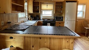 A kitchen with wooden cabinets, a central island with stools, a stove, and a refrigerator. - Centrally located, Quiet Neighborhood, 3 Minute Walk to Restaurants and Shops ✨ (Crested Butte)