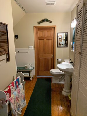 Une salle de bain avec une porte en bois, des toilettes, un lavabo et un miroir.