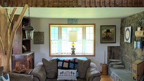 A cozy living room with a wooden ceiling, a sofa, a table, and a window with curtains. - A Rustic Retreat at Wolf Hollow Farm (Andes)