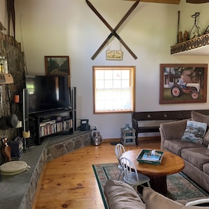 Cozy living room with a stone fireplace, television, and comfortable seating area.