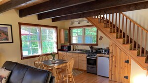 Une cuisine chaleureuse avec un plancher en bois, un coin repas avec une table et des chaises, et un escalier menant à un autre niveau.