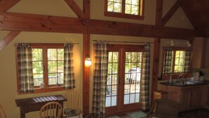 A cozy room with a wooden ceiling, a dining table with chairs, a kitchen area, and large windows with plaid curtains. - Tranquil And Peaceful Vacation Getaway Just Waiting To Welcome You (Bristol)