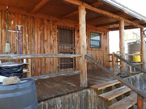 Step into this cozy cabin with a porch area featuring a wooden door, window, and bench.