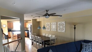 A living room with a blue sofa and patterned cushions, a dining area with a wooden table and chairs, and a kitchen in the background. - Walk to everything downtown and beach (Dewey Beach)