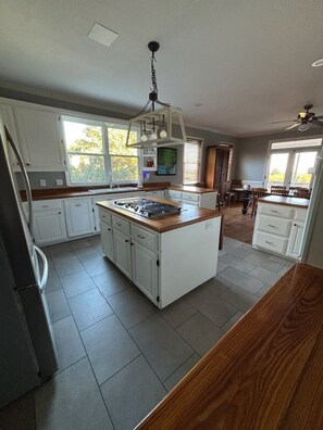 A kitchen with white cabinets, a wooden countertop, and a central island.