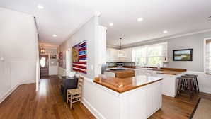 A spacious kitchen with white cabinetry, a wooden island, and a dining area with a chair. - Oceanfront Home, Stunning Views, Sun Deck, Screened Porch, Walk to restaurants! (Sullivan's Island)