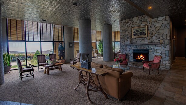 A spacious lounge with a stone fireplace, large windows, and comfortable seating.