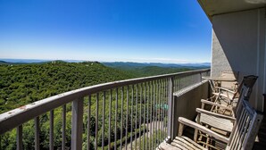 A balcony with a view of a forested mountain range.