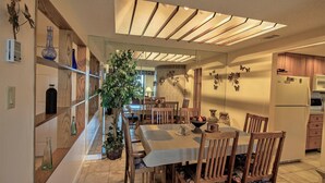 A modern kitchen with wooden cabinets, a dining table with chairs, and a large window.