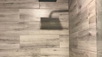 Ducha de diseño moderno, con panel de pared de madera y cabezal de ducha cromado.