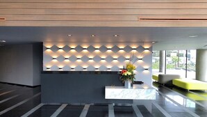 A modern reception area with a geometric light wall, a marble counter, and a yellow seating area.