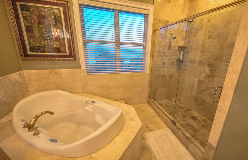 A bathroom with a freestanding bathtub, a glass shower enclosure, and a framed artwork above the window.