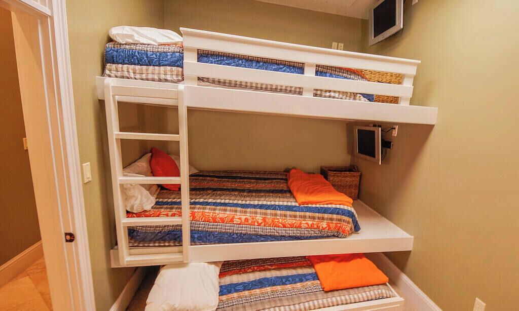 A bunk bed with a ladder, a television, and a storage drawer.
