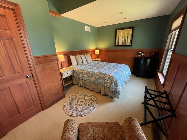 A bedroom with a bed, nightstand, lamp, dresser, and a window.