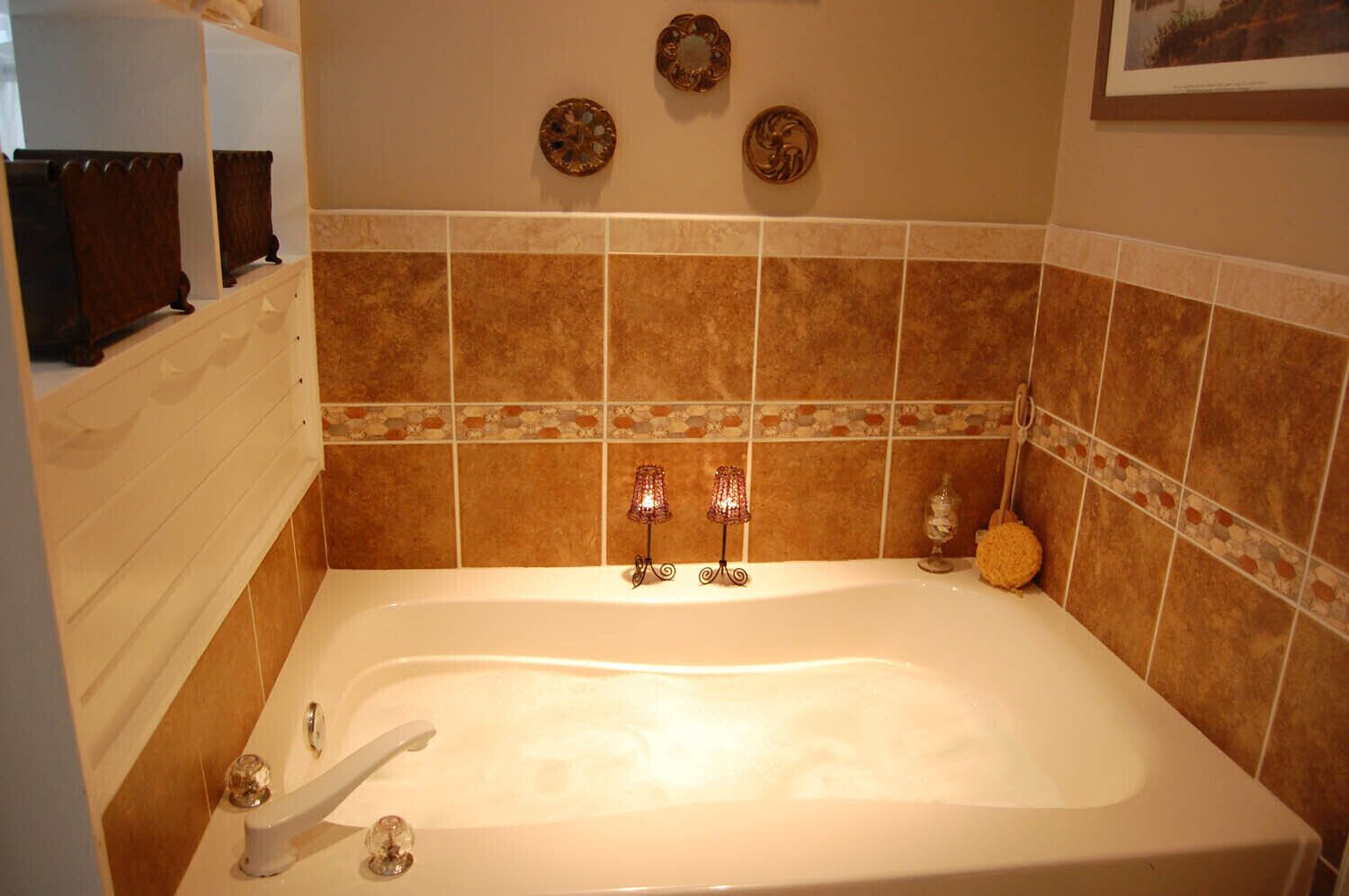 A bathroom with a bathtub, two wall-mounted lights, and a decorative tile border.
