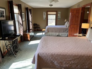 A hotel room with two beds, a TV, a desk, and a chair.