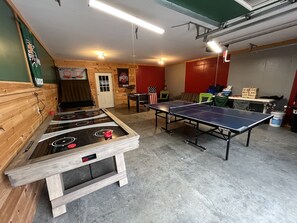 Una sala de recreación con mesa de fútbol de mesa, mesa de ping pong y mesa de billar.