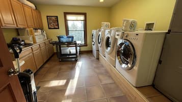 Une buanderie équipée d’un lave-linge, d’un sèche-linge et d’un chariot avec des paniers à linge.