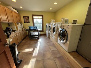 A laundry room with a washing machine, dryer, and a cart with laundry baskets.