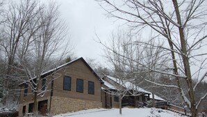 Eine Lodge mit steinverkleideter Fassade, mehreren Fenstern und verschneiter Landschaft.