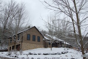 A lodge with a stone facade, multiple windows, and a snow-covered landscape. - Harvest Moon Lodge at Harvest Moon Cottages, LLC (Rockbridge)