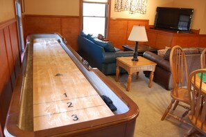 A pool table in a living room with a sofa, a television, and a lamp.