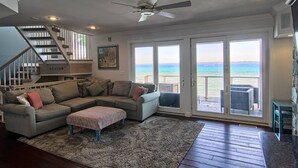 A spacious living room with a large sectional sofa, a coffee table, and a staircase leading to an upper level.