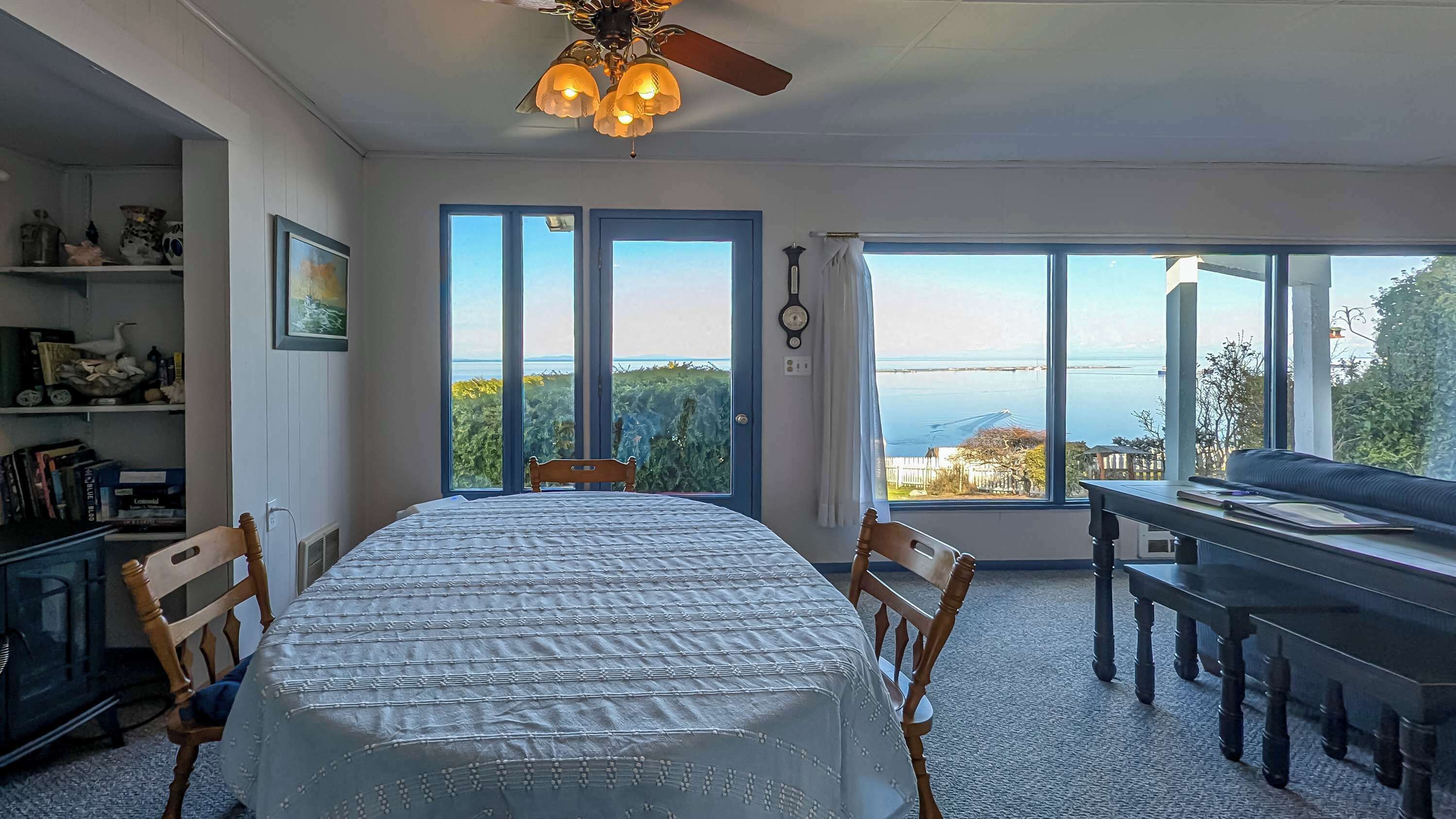 Una habitación con una cama, un escritorio y vista al mar a través de amplios ventanales.