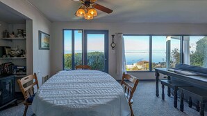 Une chambre avec un lit, un bureau et une vue sur la mer grâce à de grandes fenêtres.