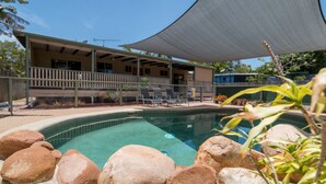 A pool area with lounge chairs and a covered patio.