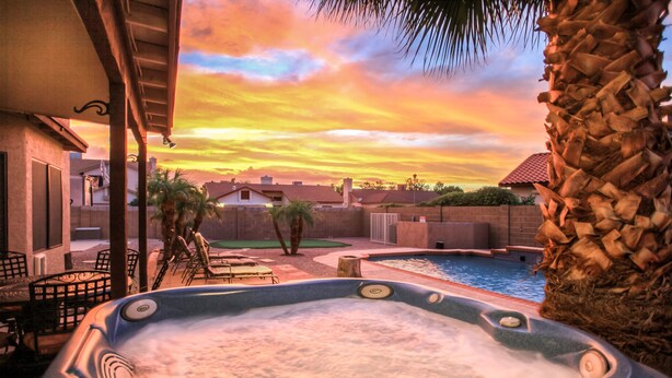 A hot tub with a view of a swimming pool and houses in the background. - Arrowhead (Glendale)