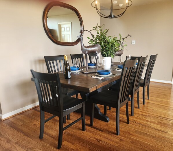 A dining room with a wooden table, black chairs, a potted plant, and a mirror on the wall.