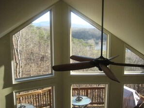 A room with a ceiling fan, large windows, and a view of a wooded area. - Dog Friendly Skyline Drive Retreat: 3 King Suites, Views & Firepit! 1pm checkout (Front Royal)