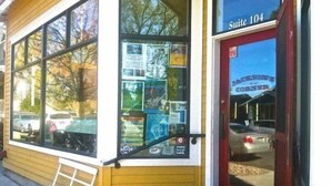 A hotel entrance with a red door labeled "Suite 104" and a window display featuring various brochures.