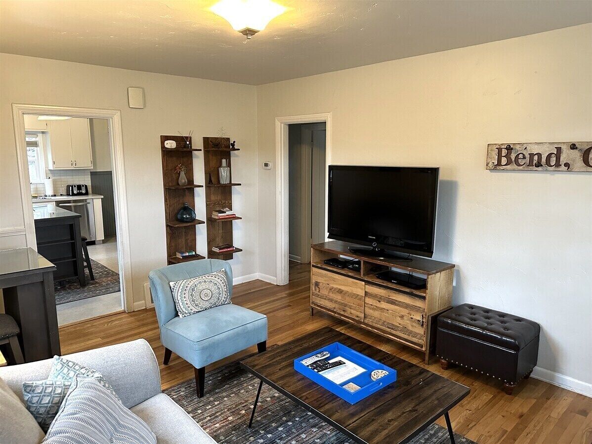 Uma sala de estar moderna com sofá, mesa de centro, televisão e unidade de entretenimento de madeira.