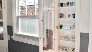 A room with a built-in shelf unit containing various glassware and a wooden bench.
