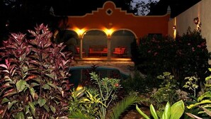 A patio area with a pool, surrounded by lush greenery and a building with a distinctive architectural style. - Tranquil Tropical Oasis in the Historic Center/ Full Size Pool (Merida)