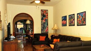 A living room with a sofa, coffee table, and artwork on the wall. - Tranquil Tropical Oasis in the Historic Center/ Full Size Pool (Merida)