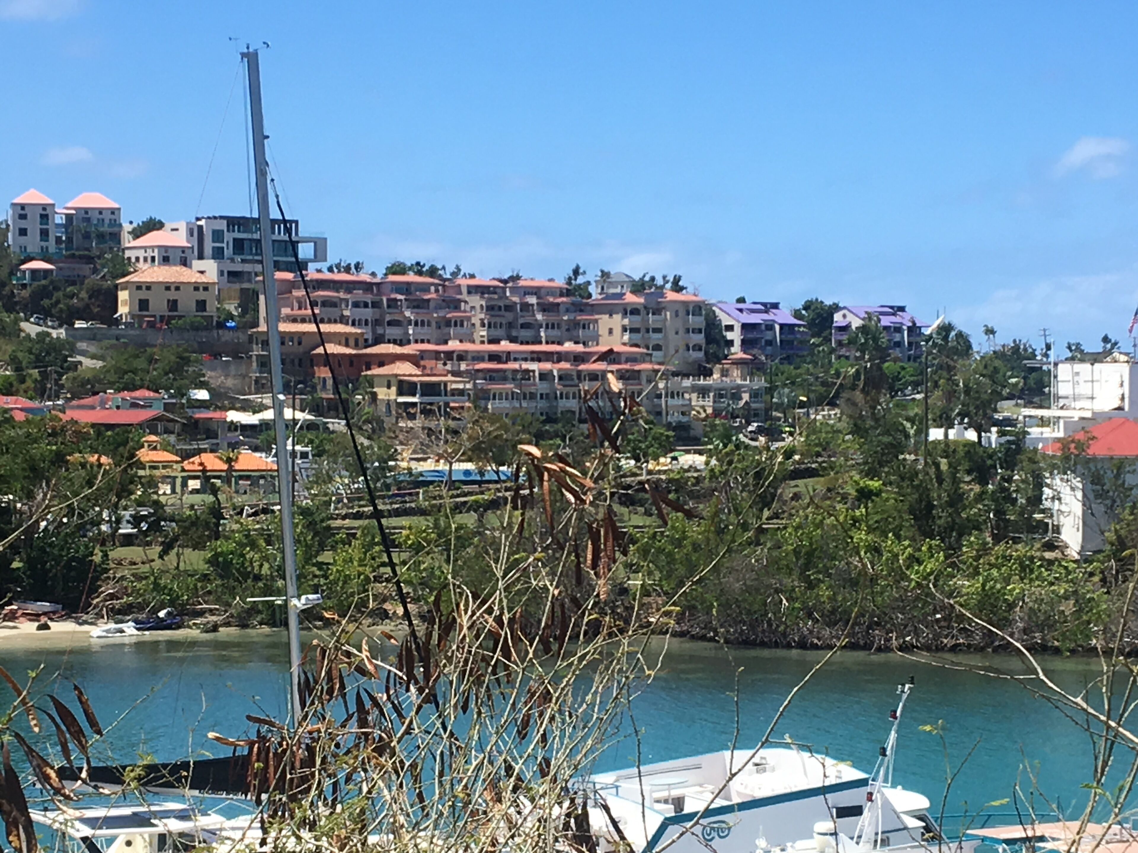 A coastal town with buildings, a marina, and a clear sky.