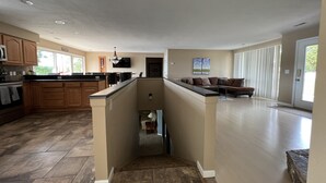 Een ruime woonkamer met keuken, eethoek en zithoek met een bank en stoelen.