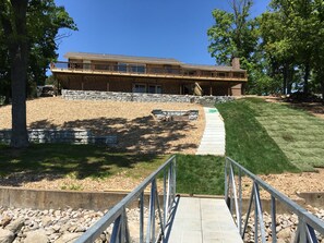 A building with a stone retaining wall, a paved pathway, and a grassy area. - 5 Bedroom, 4000 Sqft House Walking Distance To H Toad and Shady Gators (Lake Ozark)