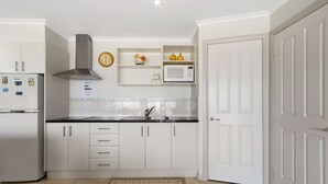 A modern kitchen with white cabinets, a stainless steel refrigerator, a microwave, and a built-in stove hood. - Resort Style Apartment (Ground Floor) - Pool & More. Pets Welcome. (Lakes Entrance)